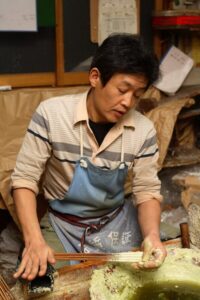 Artisan hand-dipping warousoku Japanese candles in hazel wax showing traditional layered buildup process