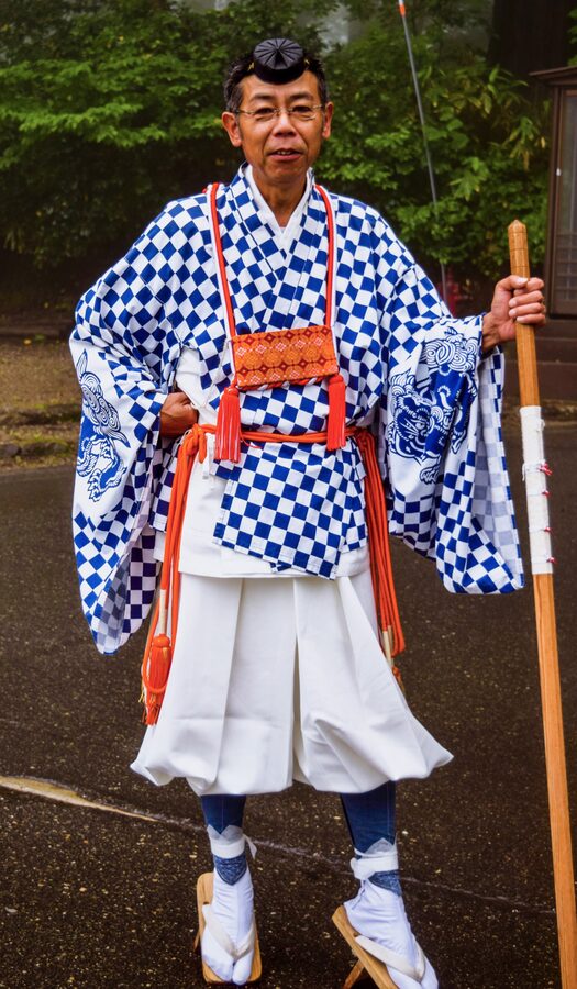 Yamabushi mountain ascetic in white robes blowing a conch shell horn